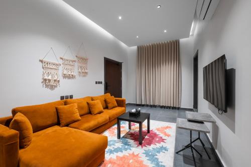 a living room with a orange couch and a table at الاورفلي للوحدات السكنية in Sulţānah