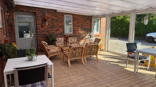 a patio with chairs and a table on a deck at Hine Bakke Bed And Breakfast in Rudkøbing