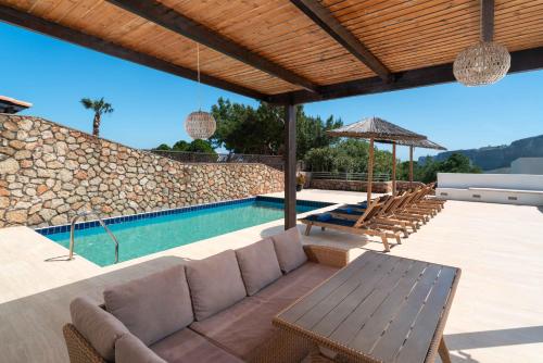 a patio with a couch and a swimming pool at Aethrion Villa Lindos in Lindos