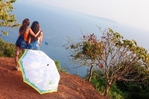 two women are standing on a hill with an umbrella at ibis Styles Goa Calangute - An Accor Brand in Calangute