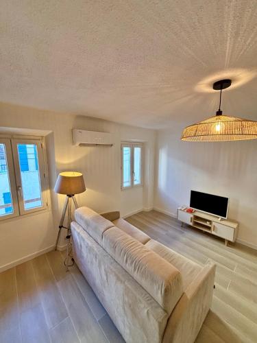 a living room with a couch and a television at L'Escale Auffan - Mourillon in Toulon
