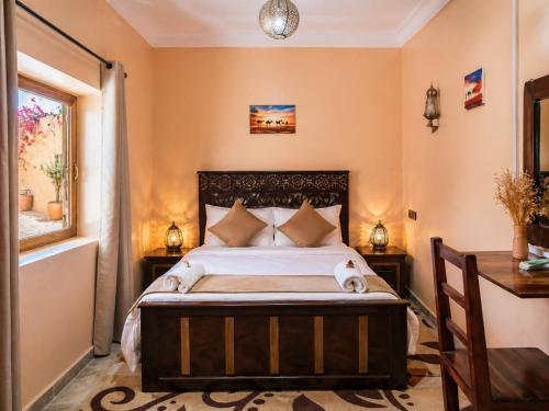 a bedroom with a bed and a desk and a window at Sahara Desert Apartment with Camel Tours & Free WiFi in Merzouga