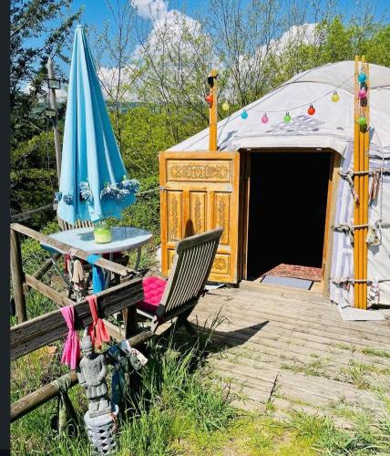 a tent with a chair and a table and an umbrella at Yourte en bord Loire avec plage privée in Saint-Jean-Saint-Maurice-sur-Loire