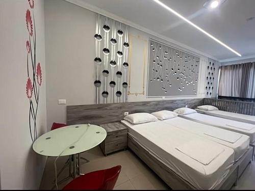 a bedroom with two beds and a table in it at Helix Apartments in Fier