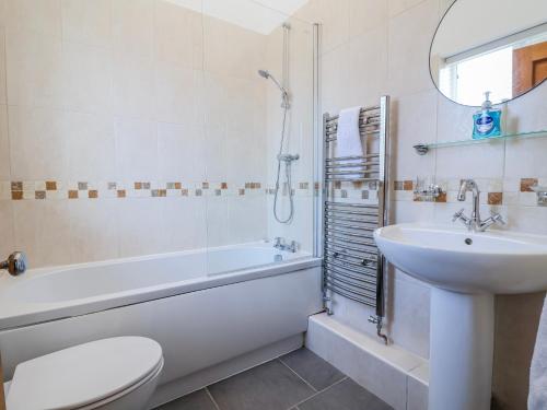a bathroom with a sink and a tub and a toilet at Elwy Cottage in St Asaph