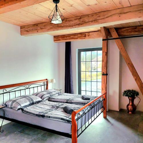 a bed in a room with a wooden ceiling at Otava apartments - Rezidence Valcha in Sušice