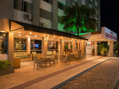 ein Restaurant mit einem Tisch und Stühlen vor einem Gebäude in der Unterkunft Hotel Gracher Praia in Balneário Camboriú