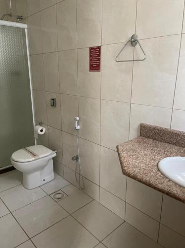 a bathroom with a shower and a toilet and a sink at Hotel Regência in São Lourenço