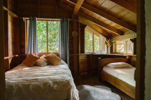 a bedroom with two beds in a wooden house at Jungle River Lodge in La Ceiba