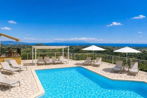 a swimming pool with chairs and umbrellas and the ocean at Ionian Balcony Hotel Apartments in Khavdháta