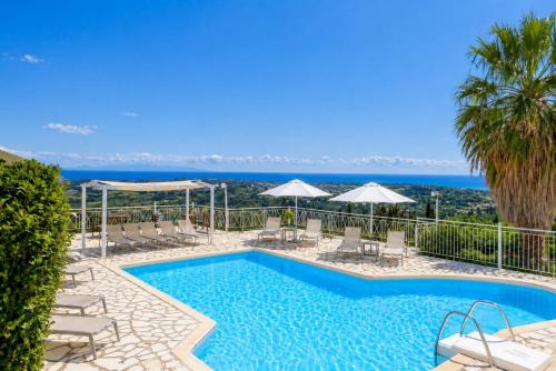 a swimming pool with chairs and umbrellas and the ocean at Ionian Balcony Hotel Apartments in Khavdháta