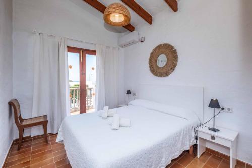 a white bedroom with a bed and a chair at Villa Binisol in Binibeca