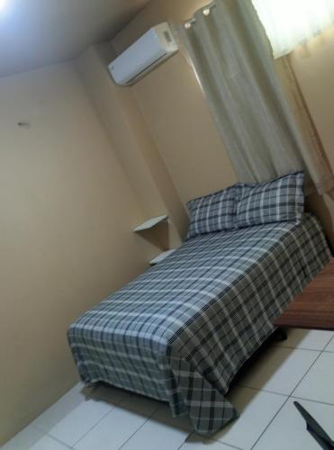 a bed with a plaid blanket and two pillows in a room at Ada H5 in Ciudad del Este