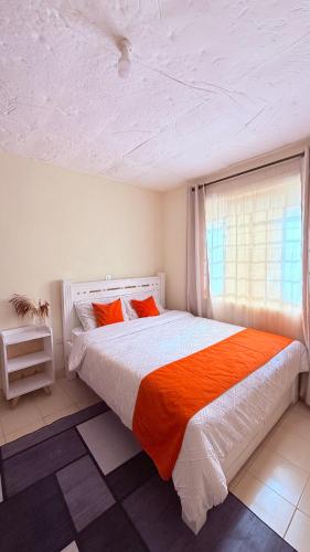 a bedroom with a bed with orange pillows and a window at Luxe homes 1b in Kabuku