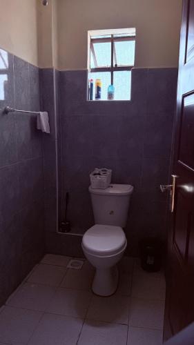 a bathroom with a toilet and a window at Luxe homes 1b in Kabuku