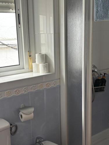 a bathroom with a toilet and a window and towels at Casa del Abuelo in Setenil