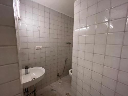 a white tiled bathroom with a sink and a toilet at Giostay Residency in New Delhi