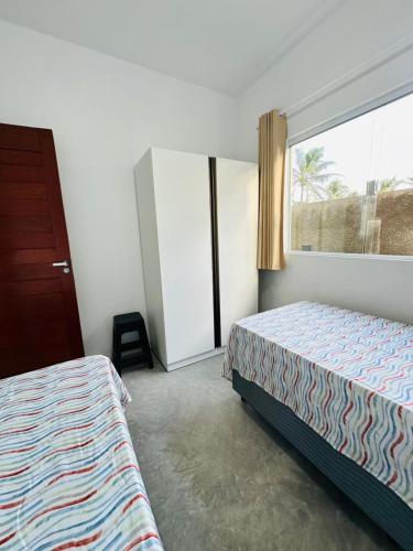 a bedroom with two beds and a large window at Chalés do Mirante in Coruripe