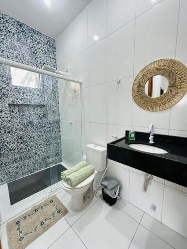 a bathroom with a toilet and a sink and a mirror at Chalés do Mirante in Coruripe
