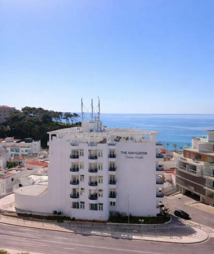 a white building with the ocean in the background at The Navigator - Ocean Heights in Olhos de Água