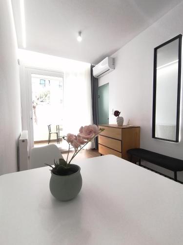 a white room with a vase with a flower on a table at Sfendamos Residence Kavala in Kavála