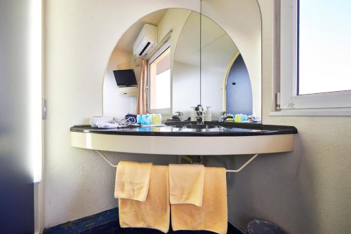 a bathroom with a sink with a mirror and towels at Hotel Select Inn Isesaki in Isesaki