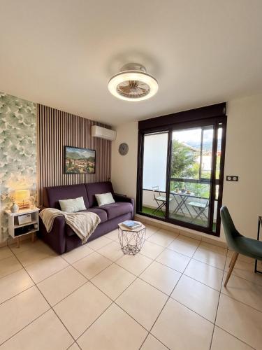 a living room with a purple couch and a window at Le Lobellia à Sainte Clotilde centre in Sainte-Clotilde