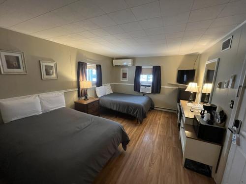 a hotel room with two beds and a desk at Martin's Motel USA in Madawaska