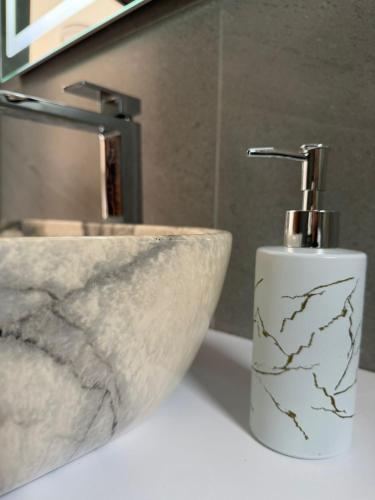 a bathroom sink with a soap dispenser next to it at Aurea Rooms in Vlorë