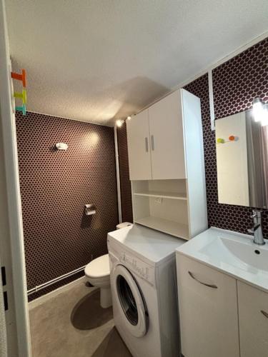 a bathroom with a toilet and a washing machine at Maisonnette cosy à 400 m de la plage - Saint Cyprien in Saint-Cyprien-Plage