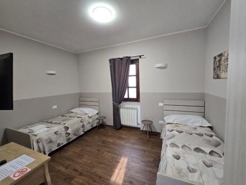 a room with two beds and a table and a window at La casa del gnocco in Masone