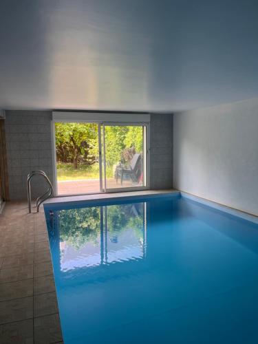 a swimming pool in a room with a person sitting in a chair at Villa avec piscine intérieure, proche Strasbourg in Holtzheim