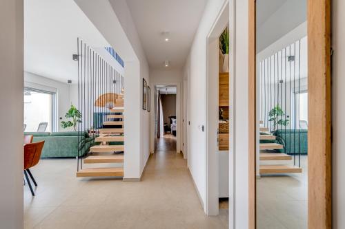 a hallway with wooden stairs and green chairs at Villa Ventula in Šuljkove Kuće