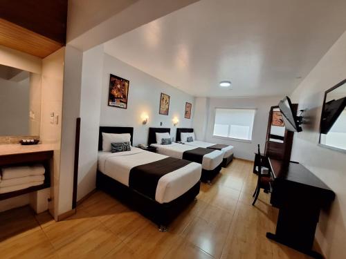 a hotel room with two beds and a desk at Epiqus Hotel in Lima