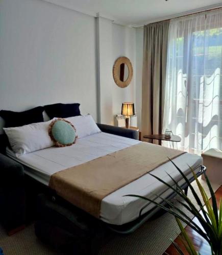 a bedroom with a large bed with a window at Pura Vida Apartmento in Ramales de la Victoria