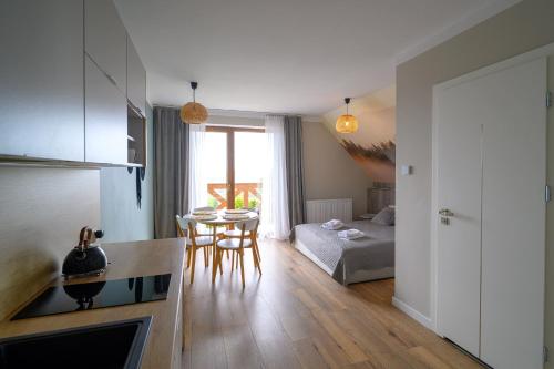 a kitchen and living room with a table and a couch at Przystanek Babia Apartamenty in Lipnica Wielka