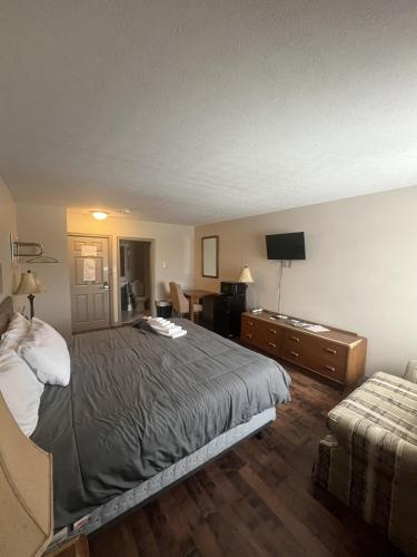 a bedroom with a bed and a dresser and a television at Gateway Motel USA in Madawaska
