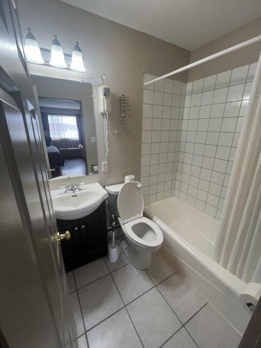 a bathroom with a toilet and a tub and a sink at Gateway Motel USA in Madawaska
