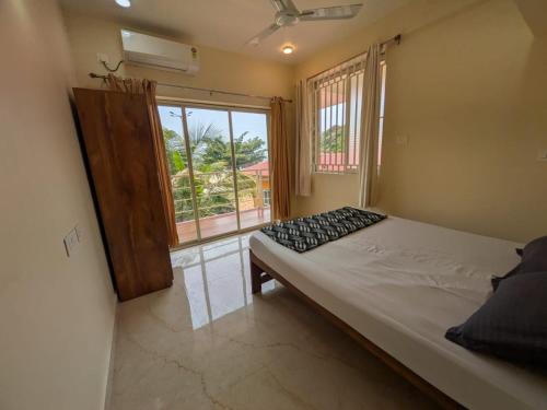 a bedroom with a bed and a large window at Shree's Seaside Homestay - Sea Pearl in Magdāl