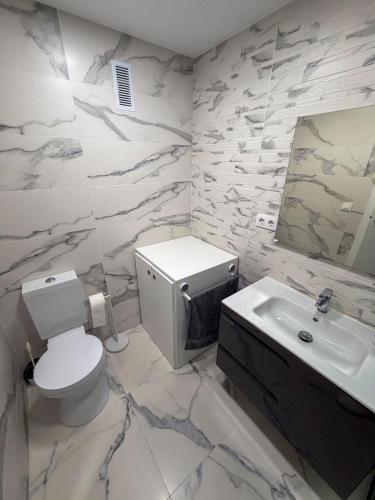 a white bathroom with a toilet and a sink at Espacio I in Cullera