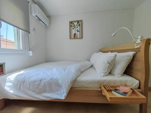 a bed with white sheets and a wooden head board at Little Kristi in Palaiókastron