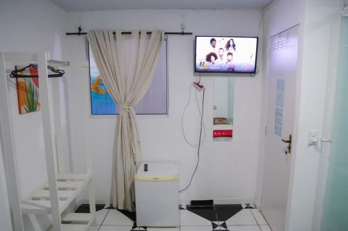 a bathroom with a toilet and a television on a wall at Donwtonw in Arraial do Cabo