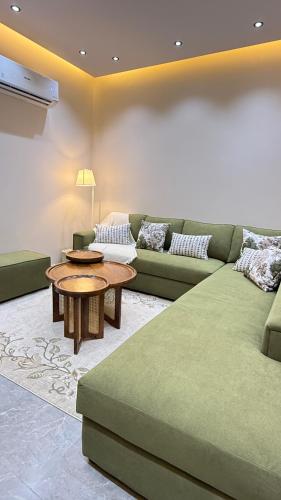 a living room with a green couch and a table at وصول ذاتي Alsumo-apartment in Jeddah