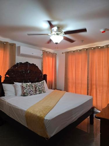 a bedroom with a large bed with a ceiling fan at Royal's 2 Bedroom suite in Kingston