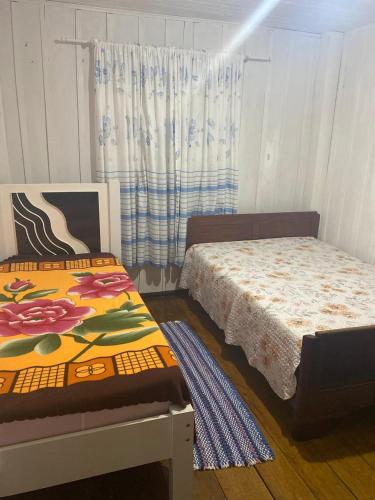 a bedroom with two beds and a window at Sítio Meu Cantinho in Benedito Novo