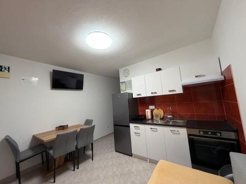 a kitchen with a table and a black refrigerator at Apartman 6 Majba in Zaglavice