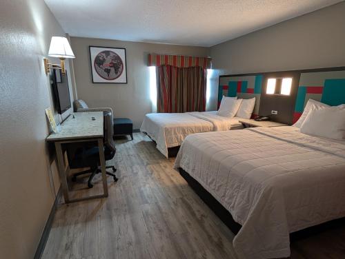 a hotel room with two beds and a desk at Ramada by Wyndham East Orange in East Orange