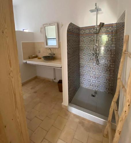 a bathroom with a shower with a sink and a mirror at ecrin mogador in Aït Sidi Saïd