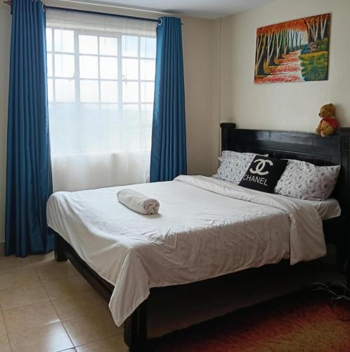 a bedroom with a bed with blue curtains and a window at Classy bedroom Ngong in Ngong