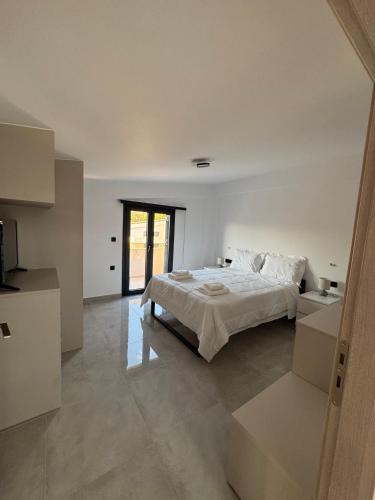 a white bedroom with a bed and a window at MareMonti VILLAS in Sidhirodhromikós Stathmós Krioneríou